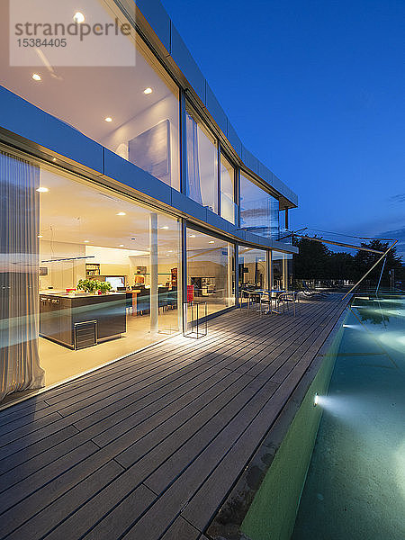 Schweiz  beleuchtete moderne Villa in der Dämmerung mit Terrasse und Pool im Vordergrund