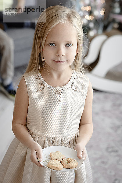 Porträt eines lächelnden kleinen Mädchens mit Keksen auf einem Teller