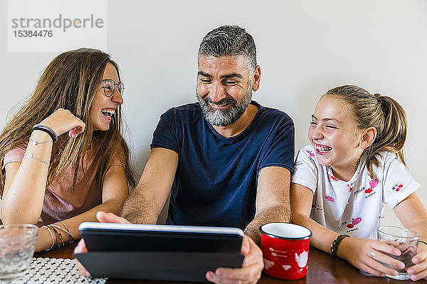 Glücklicher Vater mit zwei Töchtern mit Tablette zu Hause