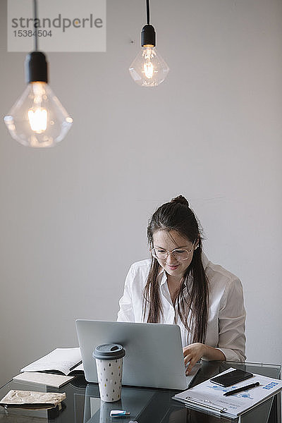 Junge Frau arbeitet am Tisch im Büro mit Laptop