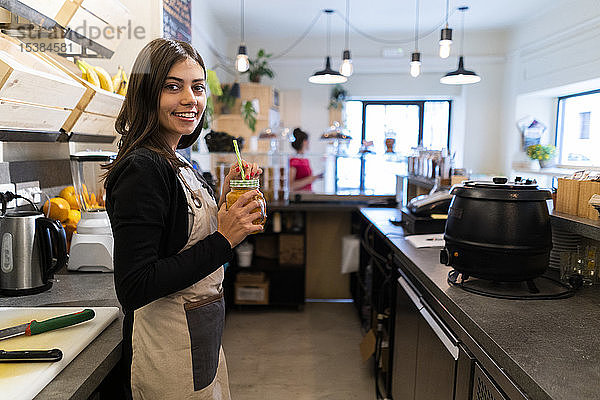 Porträt einer lächelnden jungen Frau hinter der Theke eines Cafés