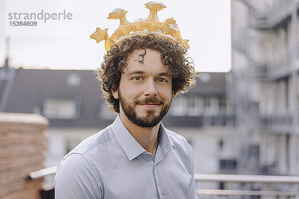 Porträt eines selbstbewussten Geschäftsmannes auf der Dachterrasse  der eine Krone trägt
