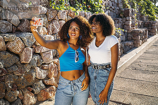 Porträt von zwei jungen Frauen  die sich mit einem Smartphone selbstständig machen