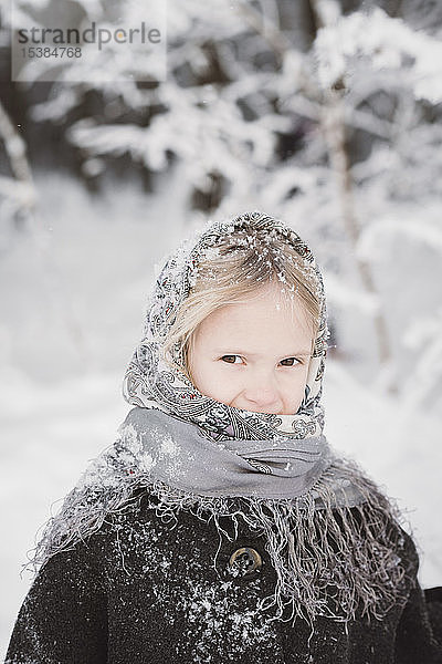 Porträt eines schneebedeckten kleinen Mädchens im Winterwald