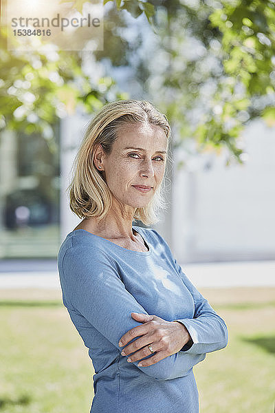Porträt einer selbstbewussten blonden Frau in einem Park