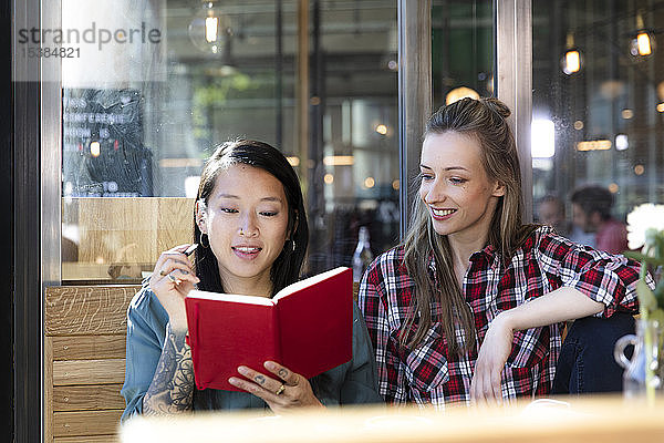 Zwei Frauen mit Buch in einem Cafe