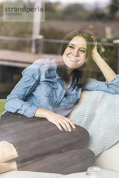 Porträt einer glücklichen Frau hinter einer Fensterscheibe zu Hause