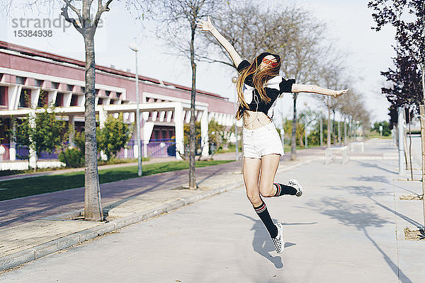 Spanien  glückliche Teenagerin springt auf eine Straße