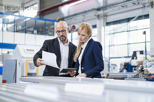 Geschäftsmann und Geschäftsfrau betrachten Papier in einer Fabrik