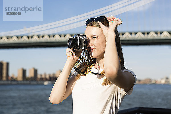 Junge Frau erkundet New York City  fotografiert an der Brooklyn Bridge