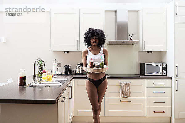 Lächelnde junge Frau trägt gesundes Frühstückstablett in der Küche