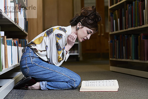 Studentin liest Buch in einer öffentlichen Bibliothek