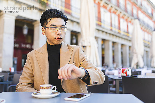 Spanien  Madrid  junger Mann überprüft die Uhrzeit in einem Café auf der Plaza Mayor