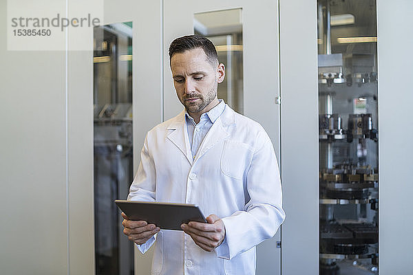 Mann mit Tablette im Laborkittel in moderner Fabrik