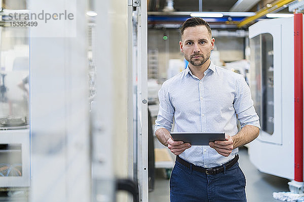 Porträt eines Geschäftsmannes mit Tablette in einer modernen Fabrik