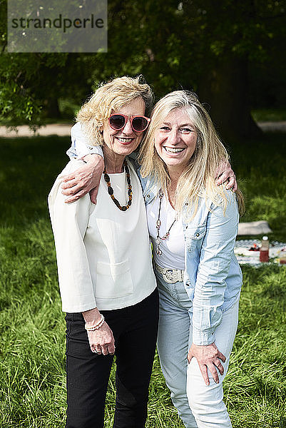 Porträt von zwei glücklichen Frauen  die sich im Park umarmen
