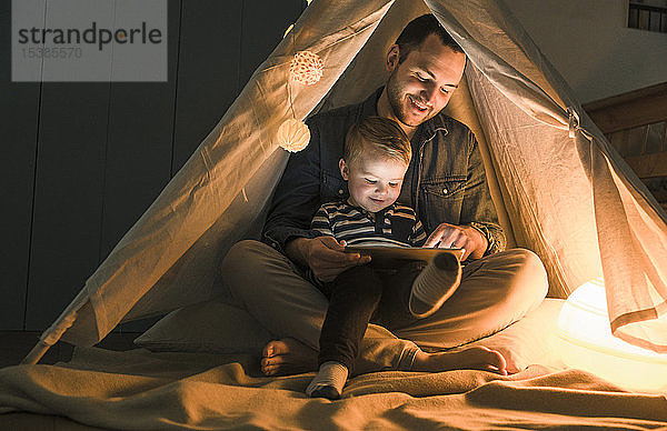 Vater und Sohn teilen sich eine Tafel in einem dunklen Zelt zu Hause