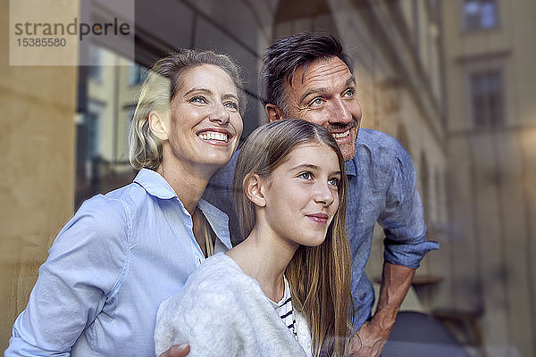 Porträt einer glücklichen Familie hinter einer Fensterscheibe