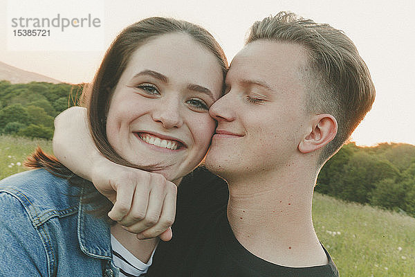 Porträt einer glücklichen Teenagerin mit Freund in der Natur am Abend