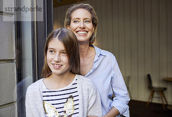 Porträt einer glücklichen Mutter mit Tochter vor offener Tür