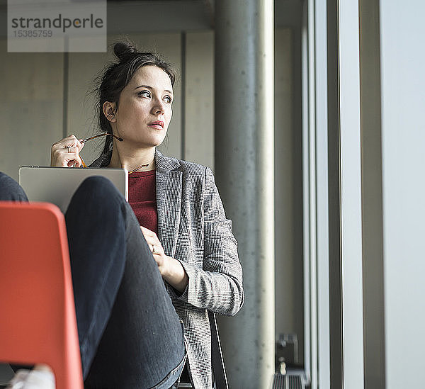 Geschäftsfrau sitzt im Büro auf einem Stuhl mit Laptop zur Seite