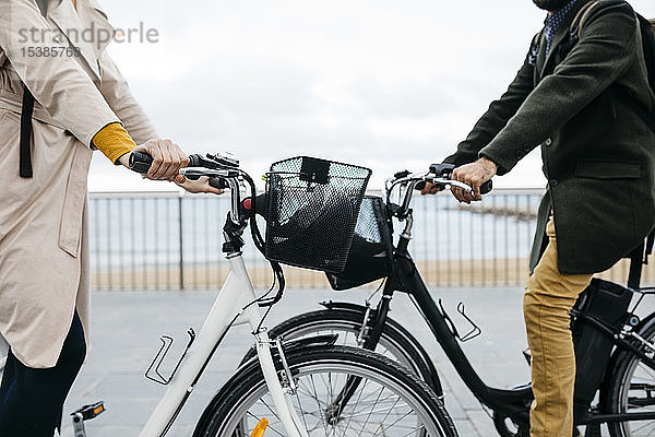 Nahaufnahme eines Paares mit E-Bikes an der Strandpromenade