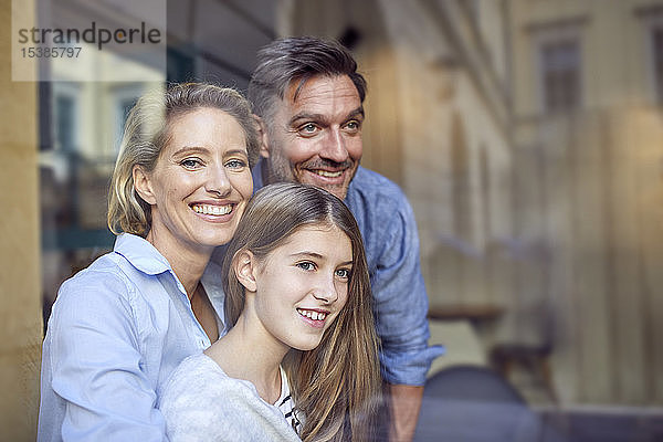Porträt einer glücklichen Familie hinter einer Fensterscheibe