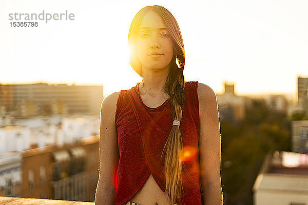 Porträt einer Teenagerin auf der Dachterrasse der Stadt bei Sonnenuntergang