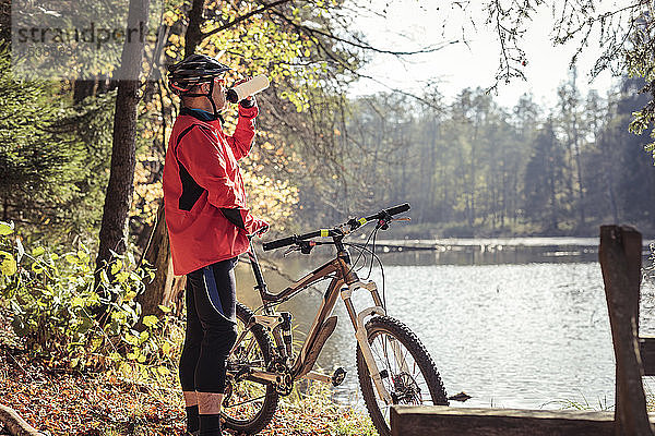 Mann mit Mountainbike bei einer Pause an einem See im Wald