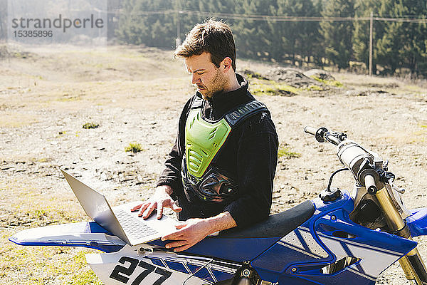 Portrait eines Motocross-Fahrers mit Laptop