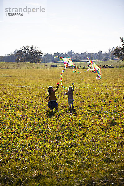 Zwei Mädchen laufen im Feld mit Drachen