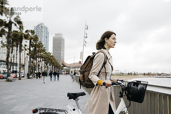 Frau mit E-Bike bei einer Pause an der Strandpromenade