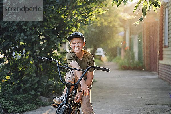 Porträt eines lächelnden Jungen mit bmx-Fahrrad auf der Strasse