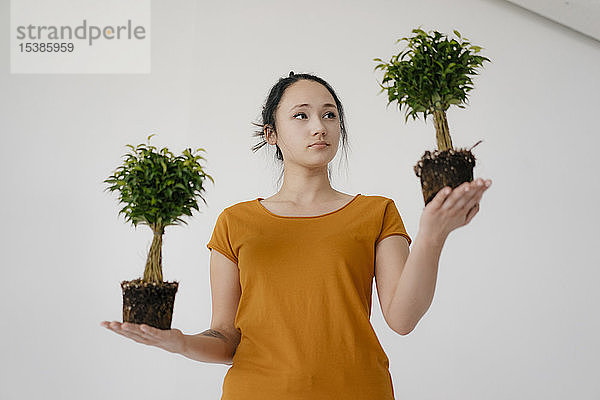 Junge Frau hält zwei Bonsai-Bäume