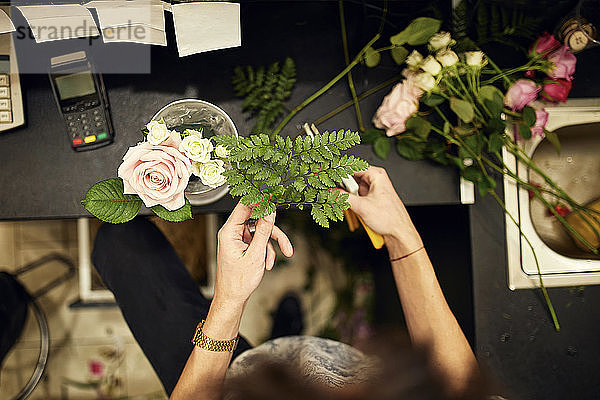 Nahaufnahme eines Floristen beim Arrangieren von Blumen im Blumengeschäft