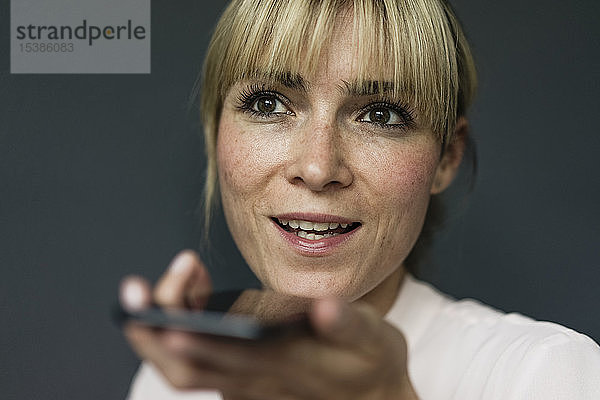 Porträt einer blonden Geschäftsfrau  die ein Smartphone benutzt