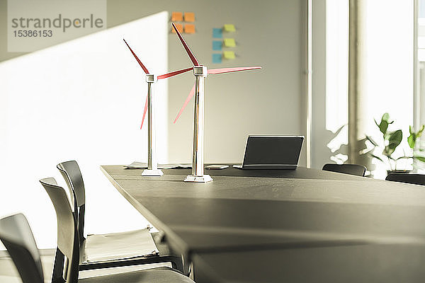 Modelle von Windkraftanlagen und Laptop auf dem Schreibtisch im Büro