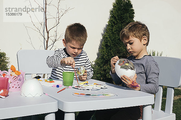 Freunde bemalen Ostereier im Garten