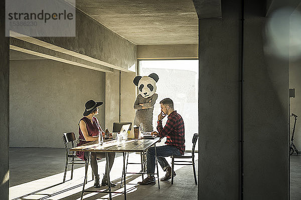 Frau mit Pandamaske beobachtet Kollegen im Büro