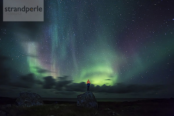 Norwegen  Lofoten  Eggum  Mann auf Felsen stehend und Nordlicht beobachtend