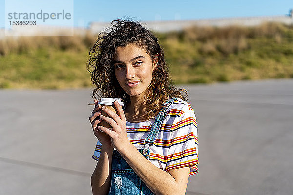 Junge Frau trinkt Kaffee aus einer Wegwerftasse