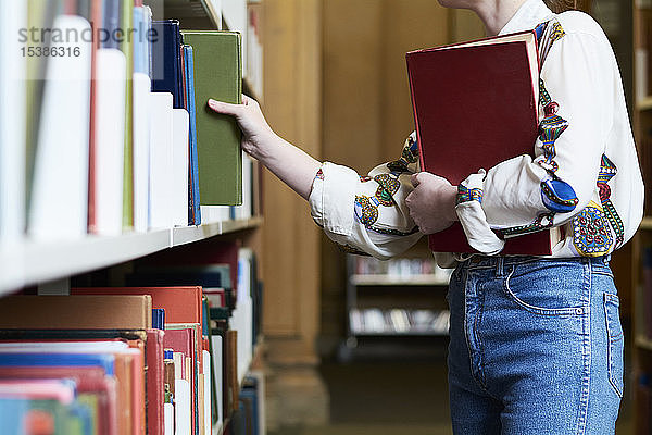 Studentin mit einem Buch in einer öffentlichen Bibliothek