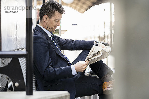 Geschäftsmann liest Zeitung am Bahnsteig