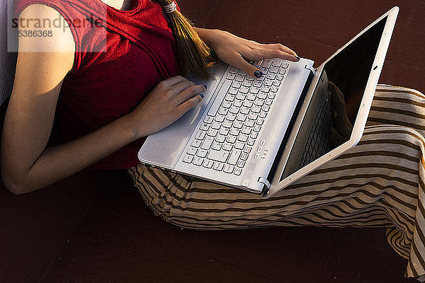 Nahaufnahme einer Teenagerin  die mit einem Laptop im Freien sitzt
