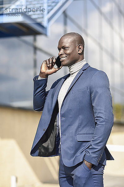 Porträt eines lächelnden Geschäftsmannes am Telefon im blauen Anzug