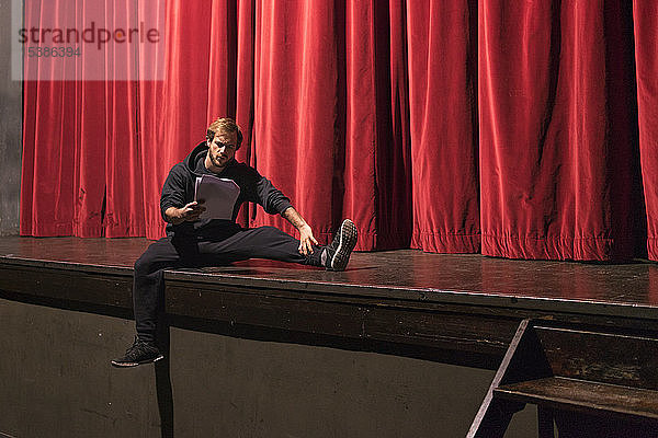 Schauspieler sitzt auf der Bühne des Theaters und studiert das Drehbuch