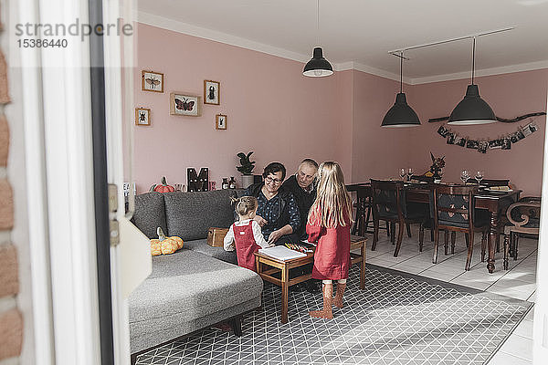 Zwei Mädchen spielen zu Hause im Wohnzimmer mit ihren Großeltern