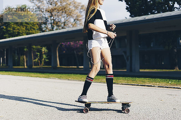 Spanien  Teenager-Mädchen fährt Skateboard auf einer Straße