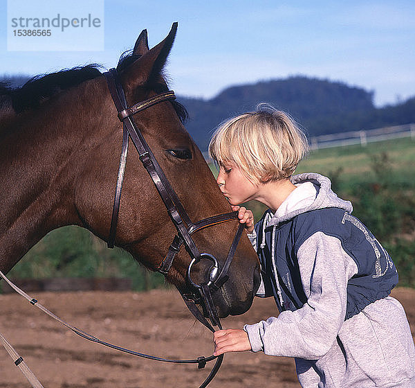 Mädchen  das ein Pferd liebevoll küsst