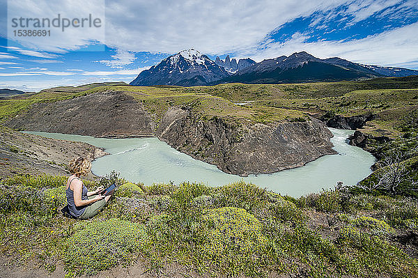 Chile  Patagonien  Frau mit Tablette an einer Flussbiegung im Torres del Paine Nationalpark